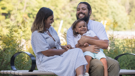 A happy family sitting on a bench on a sunny day.