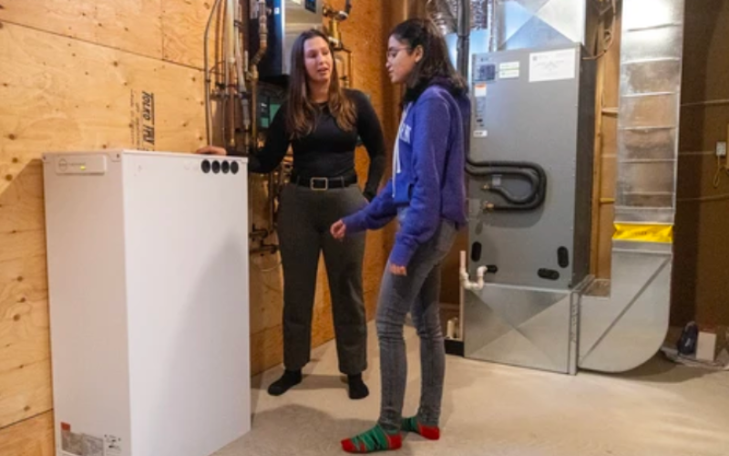 Homeowner Jaime Crncich asks Western electrical engineer Shafquat Rana about the thermal storage device in her basement. About the size of a small freezer, the device stores heat rather than electricity and is one of several features – including solar panels on the roof – designed to make the house energy neutral. Photograph taken Wednesday, Nov. 5, 2025. (Mike Hensen/The London Free Press)