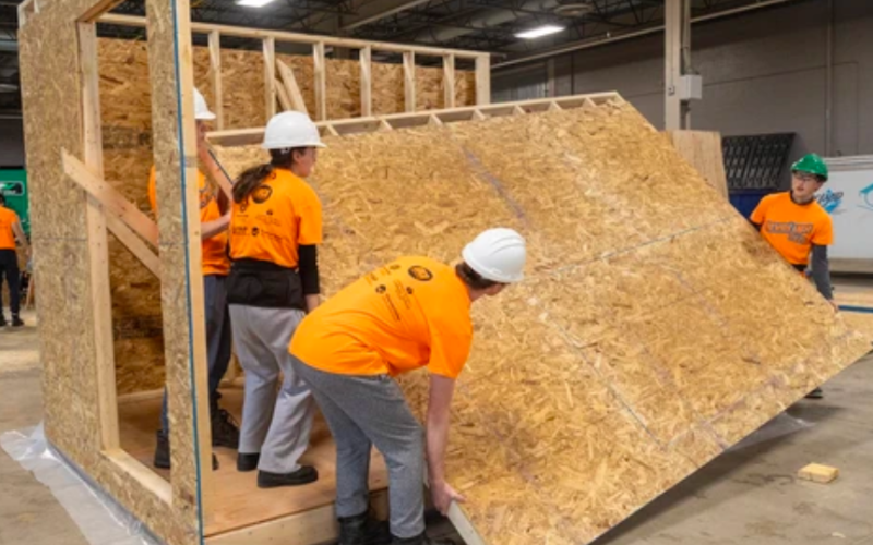 (From L-R): David Marr, 17, Ashlyn Kendall, 16, Markus Hayward, 17, and Eric Wilson, 17, all from Lucas secondary school, lift a wall they built into place while helping construct temporary homeless shelters at the J-AAR Expo Centre at Western Fair. Photographed Wednesday, Nov. 12, 2025. (Mike Hensen/The London Free Press)