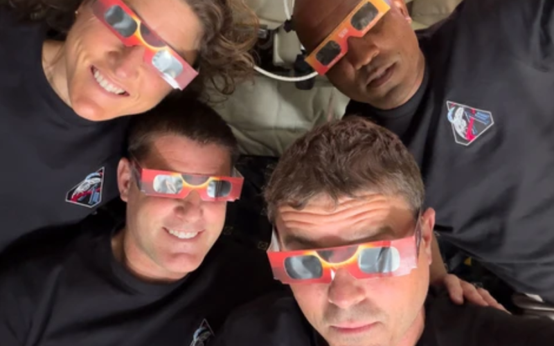 This handout picture released on April 7, 2026, by NASA shows Artemis II crew members Christina Koch (top left), Jeremy Hansen (bottom left), Reid Wiseman (bottom right), and Victor Glover (top right) using eclipse viewers to protect their eyes at key moments during the solar eclipse they experienced during their lunar flyby. (Photo by Handout /NASA/AFP via Getty Images)