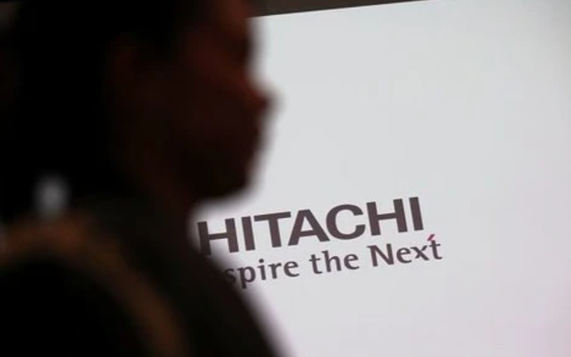 A woman passes by the logo of Hitachi prior to a press conference in Tokyo in 2019. (BEHROUZ MEHRI/AFP via Getty Images)