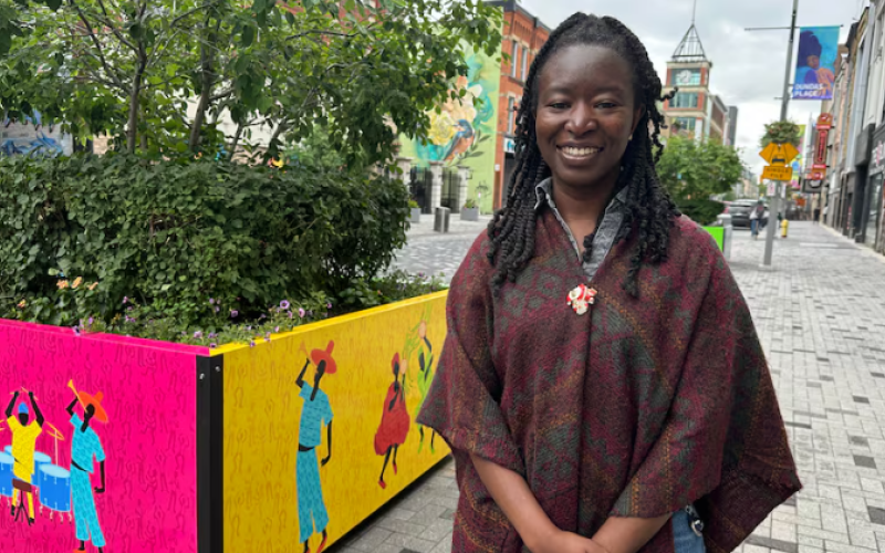 Artist Amsa Yaro stands beside her newly unveiled artwork on planter boxes on Dundas Street in downtown London. (Jessica Singer/CBC)