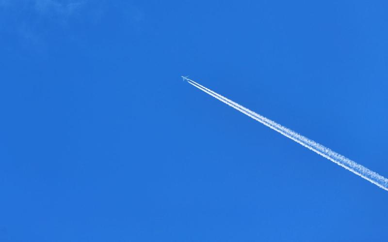 Airplane flying high in clear blue sky leaving a long contrail. (Christina & Peter/PEXELS)