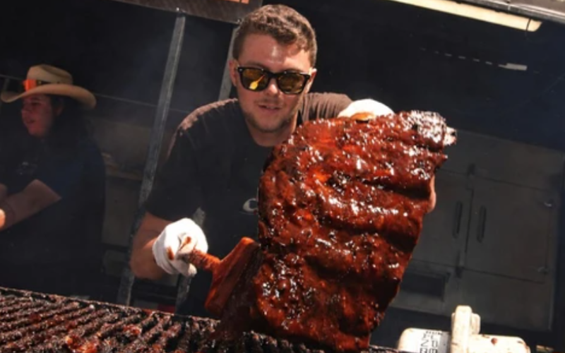 Stuart MacTaggart, of Boss Hogs BBQ, lifts a freshly sauced rack of ribs from the grill during Ribfest at Victoria Park on Monday, Aug. 3, 2026. (Matthew Daldalian/The London Free Press)